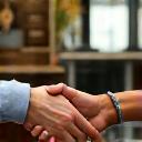 Two people shaking hands over a cafe table